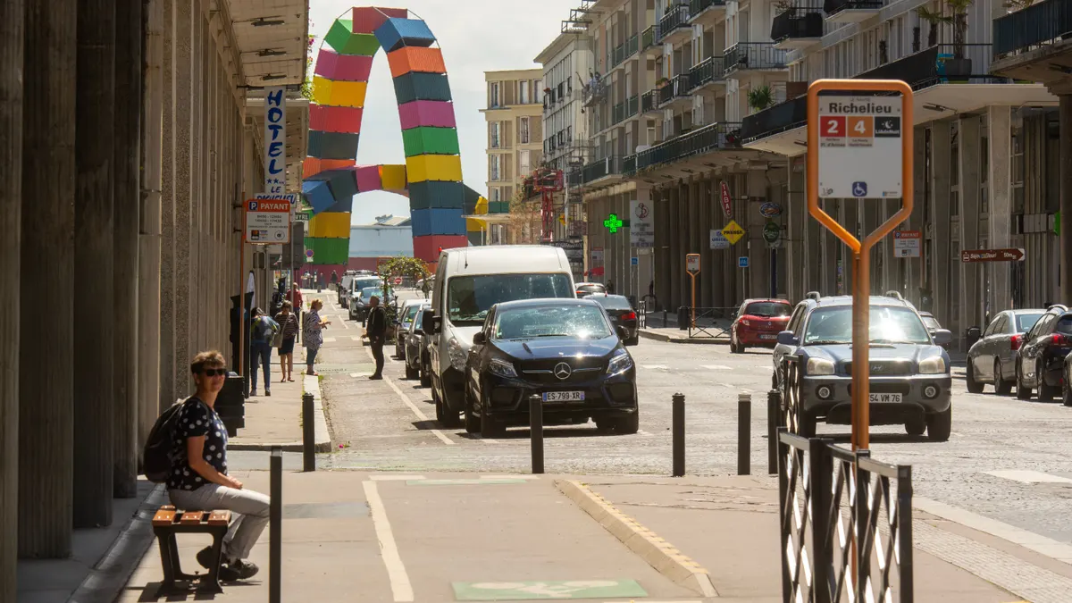 Scène de rue animée au Havre avec des sculptures urbaines colorées et la vie citadine.